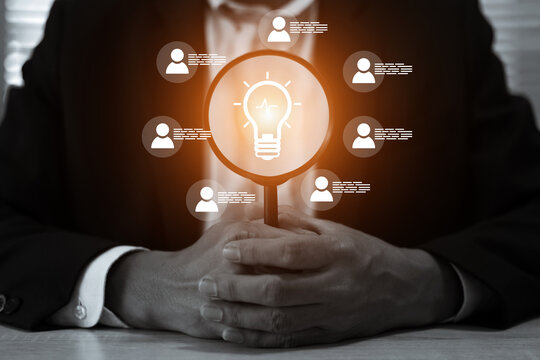 Businessman's hand with HR human resources icons on light bulb for leader or group teamwork people officer or business planning or team player and personnel management job performance.