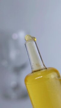 Clear yellow liquid slowly coming out from a transparent syringe. Beauty serum or cosmetic injection tool concept. Glossy fluid texture.