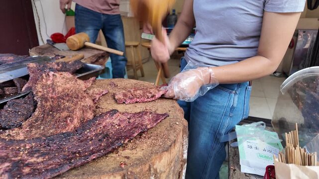 Traditional Yunnan Niuganba Beef Jerky Being Pounded by Hand in a Local Shop in Weishan Ancient Town, China