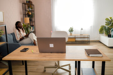 Fototapeta premium Workspace with a desk, laptop, and person relaxing in a living room