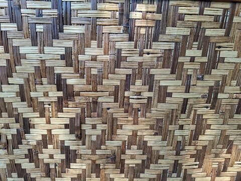 A detailed close-up shot of a traditional woven bamboo wall panel showcasing an intricate crosshatch geometric pattern.