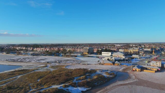 Aerial perspective reveals a winter cityscape with snow-covered ground and green earth patches. rural landscape, Wainfleet, Village, Skegness in morning sunrise wintertime.