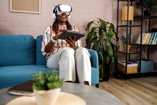 Woman wearing virtual reality headset using a tablet at home in the living room