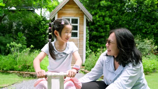 Happy Asian Child Playing Outdoors with Caring Female Guardian in Green Garden, Family Bonding and Childhood Lifestyle Concept Under Natural Sunlight