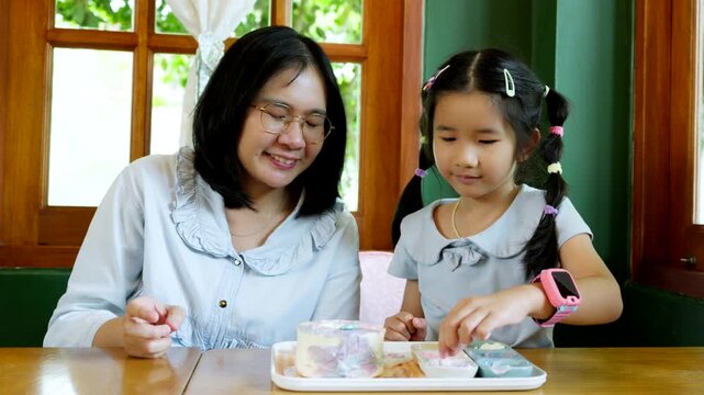 Asian Child Decorating Cake with Caring Parent at Home, Family Bonding and Quality Time During Creative Indoor Activity