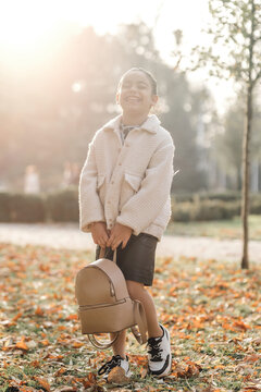 A girl walks through an autumn city, a photo shoot. Evening time, golden hour
