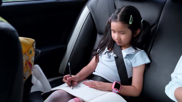Asian Child Wearing Seat Belt While Drawing in Car During Family Road Trip, Safe Travel and Child Passenger Safety Concept
