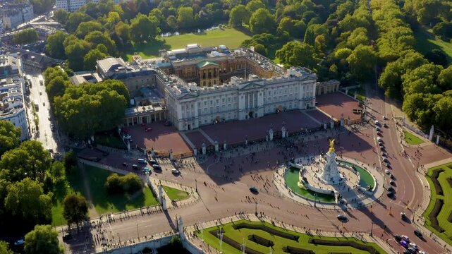 Aerial drone view of Buckingham Palace royal residence, the Victoria Memorial and tourists at the palace gates near St James Park in Westminster, London, United Kingdom, on a sunny day.