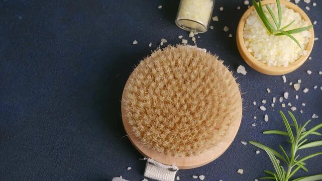 Dry body brush with bath salts and rosemary on dark background