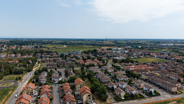Aerial View of a Residential Suburb: An expansive drone shot reveals a sprawling suburban neighborhood characterized by rows of detached houses and townhouses. Melegnano, Milan, Italy
