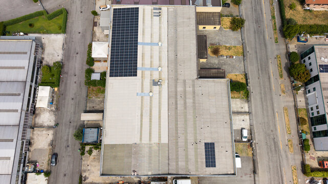 Aerial view of an industrial logistics area in Melegnano, Italy, featuring warehouse rooftops with solar panels and sustainable energy infrastructure.