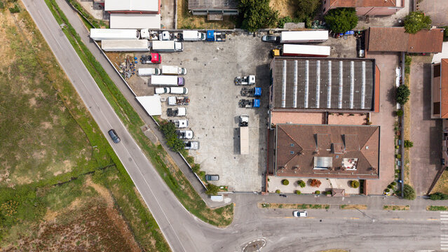 Industrial Complex Aerial View: An overhead perspective reveals a bustling industrial complex with a network of warehouses, trucks, and administrative buildings. Melegnano, Milan, Italy