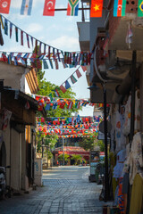 Fototapeta premium Narrow tourist street decorated with international flags in Kaleici old town Antalya Turkey