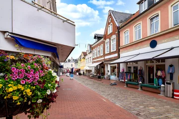 Shopping street in Kappeln featuring retail stores, colorful flower displays, historic buildings and a pedestrian street beneath a blue sky.. Germany © EKH-Pictures
