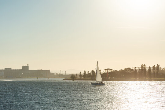 Sailboat on sunlit day sailing out of Newcastle Harbour