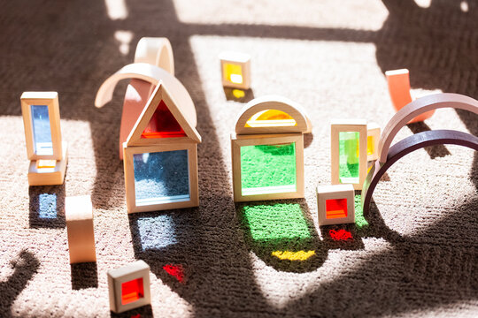 Light shining through colourful toy bocks set up by child on sunlit floor