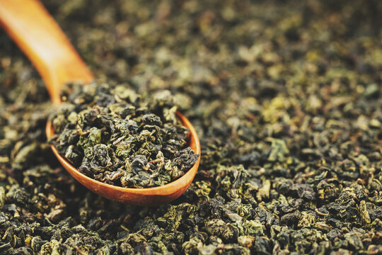 Premium dried oolong tea scoop on minimal solid background