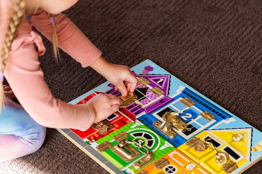 child working on colourful lock puzzle board on floor