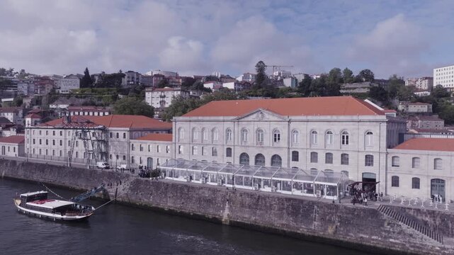Aerial views of river Douro and a river boat docking to load passengers at a large old building. Porto, Portugal