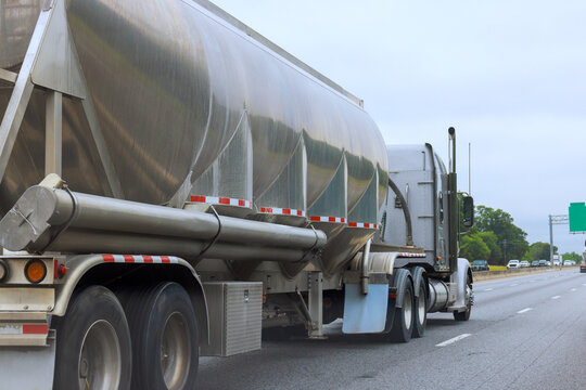 Truck moves along highway with silver trailer in early morning light.