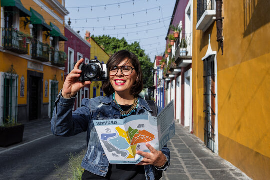 senior latin woman traveling and holding a tourist map in Mexico Latin America, hispanic adult female tourist in colonial city 