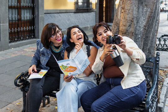 senior latin women friends traveling holding a tourist map in Mexico Latin America, hispanic mature adult or middle age female tourist in colonial city 