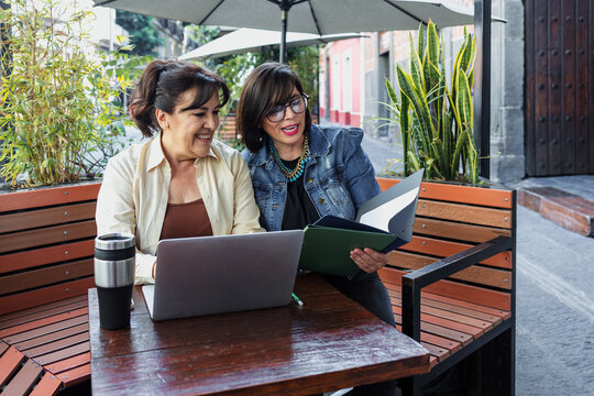 senior latinas group of women friends using laptop and having fun outdoors in terrace in Mexico Latin America, mexican teamwork working with computer  