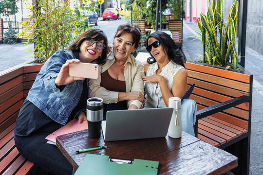 senior latinas group of women friends using laptop and taking photo selfie outdoors in terrace in Mexico Latin America, mexican teamwork working with computer  