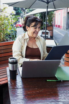 senior latin woman using laptop and having fun outdoors in terrace in Mexico Latin America, mexican female working with computer  
