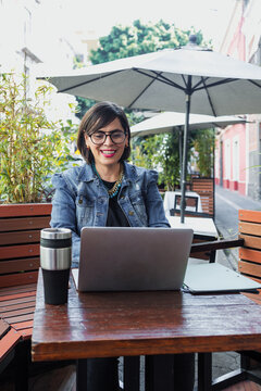 adult latin woman using laptop and having fun outdoors in terrace in Mexico Latin America, mexican female working with computer  