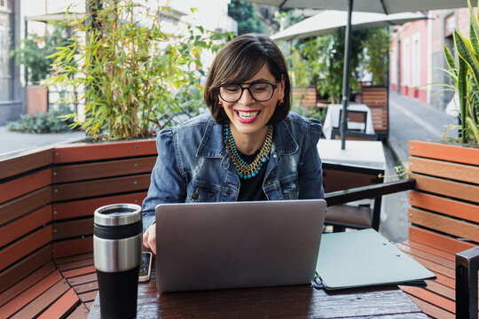 adult latin woman using laptop and having fun outdoors in terrace in Mexico Latin America, mexican female working with computer  