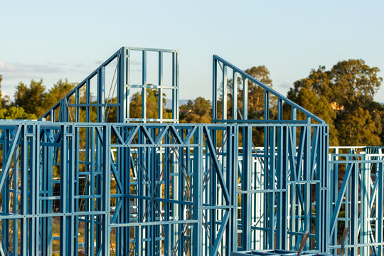 Blue steel frame of house under construction in Australian suburb at sunset