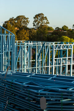 Blue steel frame of house under construction in Australian suburb at sunset