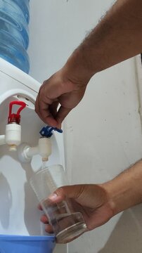 Hands operating a water dispenser tap for fresh water.
