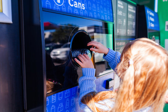 child returning plastic bottle for recycling at return and earn collection point in Australia
