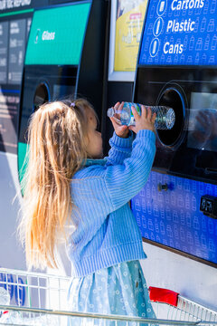 child returning plastic bottle for recycling at return and earn collection point in Australia