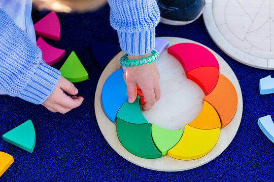 Little girls hands doing colourful puzzle game at preschool