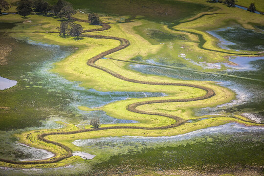 Aerial view of winding river through grassy floodplain