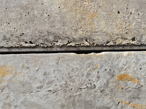 A horizontal line gap between two weathered precast concrete panels with rustic stains, close up.