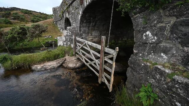Old stone bridge with wooden gate hanging underneath for protecting animals entering the water