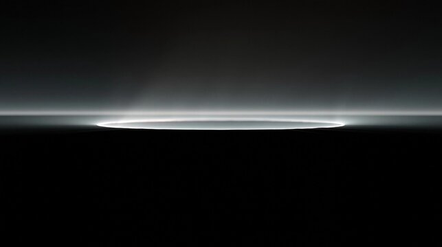 Black and white photograph of a circular light strip in the middle of a dark room. the light strip is white and appears to be glowing, creating a contrast between the two colors.