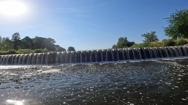 POV action shot of a fisherman getting a bite and reeling in a European chub (Squalius cephalus) near a river weir.