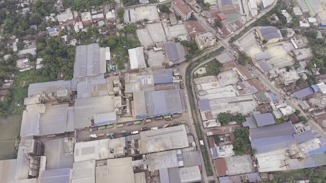 Drone shot with a slight left-curving forward movement across an industrial zone in Khajanagar, Kushtia, featuring factories, rooftops, infrastructure, and the rural surroundings.