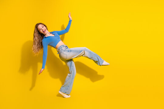Cheerful young woman in vibrant casual outfit posing dynamically against a bright yellow background, smiling confidently