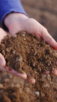 Hands dropping farm field soil close up slow motion