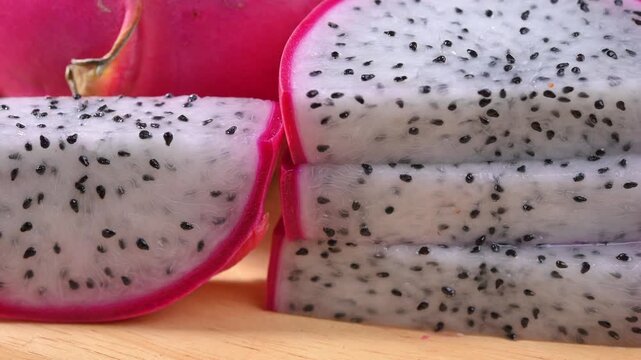 Fresh dragon fruits displayed on a rustic wooden plate, highlighting their vibrant pink skin and natural freshness. A healthy tropical fruit rich in fiber, antioxidants, and vitamin C, perfect for con