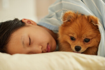 夏の家のリビングで可愛いポメラニアンの子犬と一緒に寝ている子供の様子 © zheng qiang