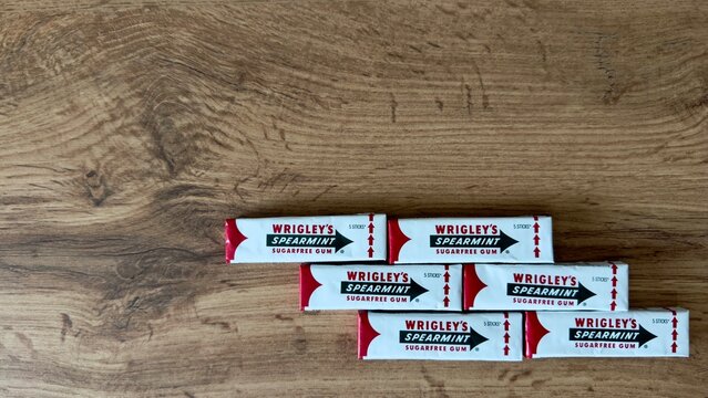 Wrigley's spearmint chewing gum packs are arranged on a wooden table in top view. The image represents branded confectionery packaging, retail display, and consumer products.