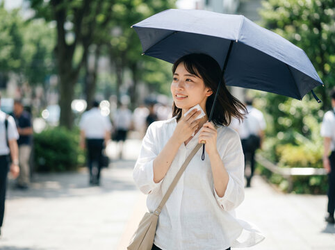 猛暑の街中で紺色の日傘を差し、シートで首元の汗を拭き取る笑顔の女性