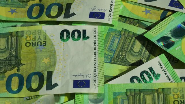 Macro close-up of many 100 euro notes focusing on fine details, security elements and texture, illustrating wealth and cash money concept. 4K Video.